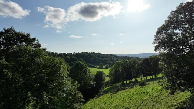 Vol au dessus de la campagne fran&ccedil;aise avec paysage de for&ecirc;t et de champs d'herbe verte sur fond de cel bleu avec nuages
