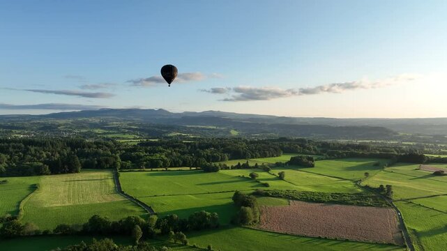 vue a&eacute;rienne drone vol en montgolfi&egrave;re au-dessus de la campagne verdoyante en france,  au cr&eacute;puscule avec ciel bleu et quelques nuages. Illustration loisir extr&egrave;me