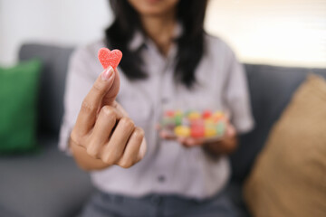 Close Up Of Woman Hands Holding Sugar Candy With Heart Shape Against Blurred Background