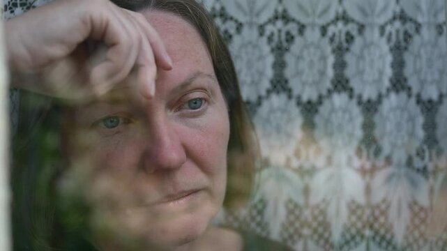 Portrait of mature adult caucasian female sad and depressed looking out the window, mental health and state of mind concept