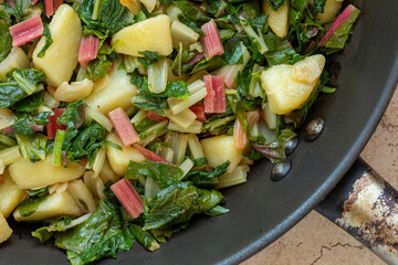Close up view of South Croatian Blitva dish on frying pan. The dish is made with boiled potatoes, swiss chard, garlic, and olive oil. 