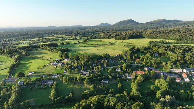 Balade a&eacute;rienne au-dessus de l'Auvergne sauvage, avec village en contre bas et le Puy-de-D&ocirc;me en arri&egrave;re-plan, montagne embl&eacute;matique de la r&eacute;gion