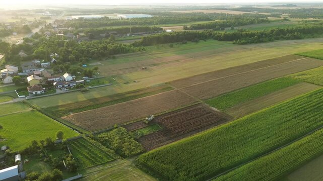 Aerial shot of machinery reaping crops on vast farmland