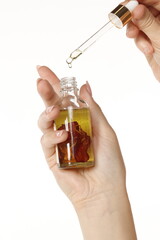Hand holding a cosmetic bottle with a dropper, isolated on white background.