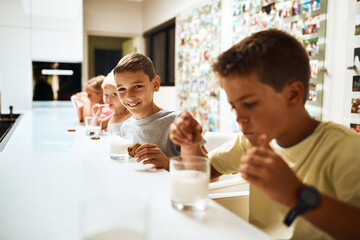 Children, siblings and drinking with cookies in milk for snack, eat or sweet combination at home. Group of young kids with smile, meal or food for healthy calcium, beverage or amino acids in kitchen