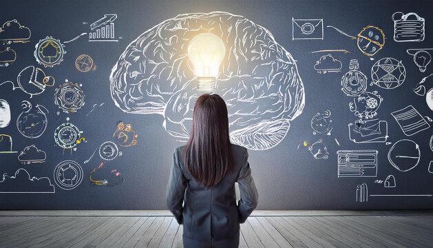 ビジネススーツを着た女性が背を向けて立っており、彼女の前には巨大な脳のイラストが描かれた黒板があります。脳の中央には輝く電球が配置され、アイデアや創造性を象徴しています。黒板にはビジネスやテクノロジーに関連するアイコンや図が散りばめられ、知識や発想の広がりを表現しています。generative AI