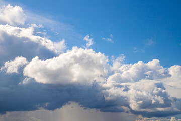 Fluffy white cloud and blue sky above. Thundercloud and rain below. Divine heaven