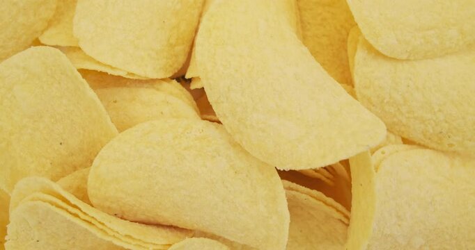 potato chips rotating close-up, top view. Golden fried Crispy potatoes chips. Background for unhealthy fatty food, snack for beer.