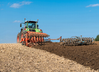 Tractor with 7-share reversible plow and packer cultivating the field after the grain harvest - 2248