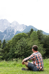 Naklejka premium Portrait of a Young Adult Man Resting in the Mountain Valley, lying on the ground
