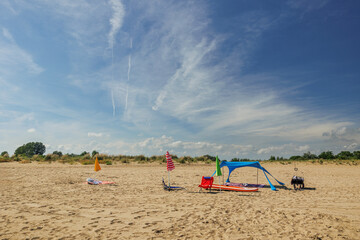 panoramica su parte di una spiaggia vicino al mare con alcuni ombrelloni, asciugamani ed altri...