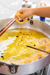 A woman is cooking picarones in a pan.