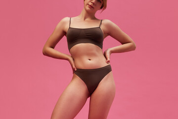 Cropped image of young woman with skinny body, slim waist posing in underwear against pink studio background. Concept of female beauty, body and skin care, cosmetology, sport, health