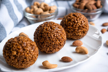 Healthy raw dessert, bliss balls of nuts cashew and almonds on white plate. Energy balls for healthy eating. Gluten off, sugar free candies made of nuts.