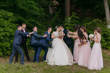 A group of people are posing for a picture, with a bride and groom in the center. The bride is wearing a white dress and the groom is wearing a suit