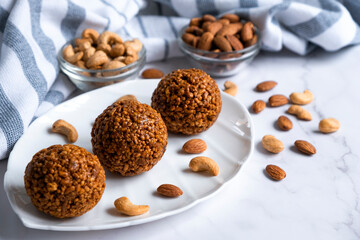 Cookie balls made of biscuit crumbs, cashew and almons nuts and caramel on white plate. Easy recipe of homemade dessert without baking. Bliss balls for tea time.