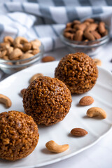 Healthy raw dessert, bliss balls of nuts cashew and almonds on white plate. Energy balls for healthy eating. Gluten off, sugar free candies made of nuts.