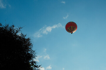 A colorful hot air balloon floating in a clear blue sky, standing out against the bright backdrop.