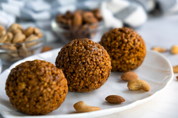 Homemade cereal bars made of oatmeal crumbs, cashew and almons nuts and caramel on white plate. Easy recipe of homemade dessert without baking. Bliss balls for tea time.