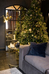 Christmas interior with a beautiful Christmas tree, sofa, light bulbs and dark background.
