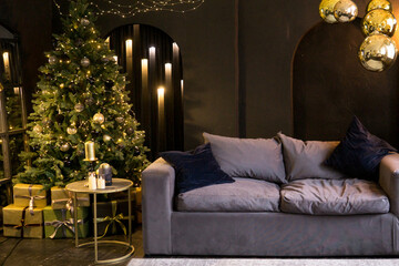 Christmas interior with a beautiful Christmas tree, sofa, light bulbs and dark background.