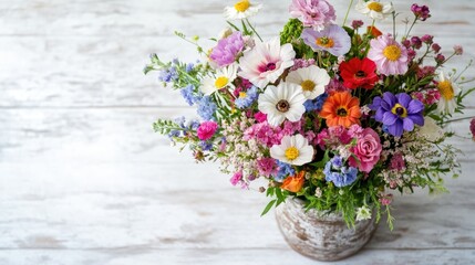 Top view of a bouquet of mixed flowers in a rustic vase on a whitewashed table -
