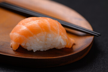 Nigiri sushi salmon on wooden plate with chopsticks, Japanese food