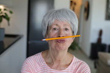 Senior woman holding a pencil between lips and nose