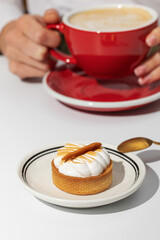 Caramel meringue tart and woman holding coffee on table