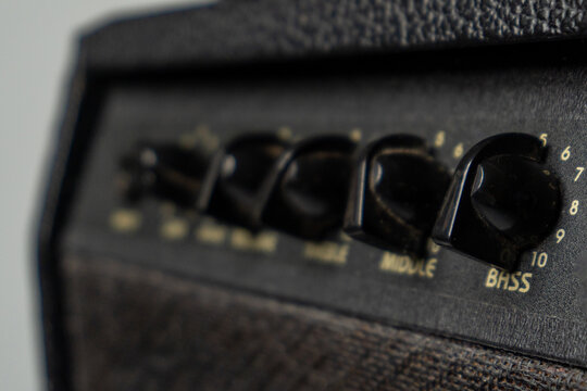 Close-up of black guitar amplifier knobs with numbers on a textured surface.