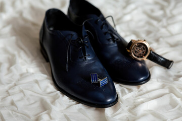 A pair of shoes and a watch are displayed on a white surface. Concept of elegance and sophistication, as the combination of the shoes and watch suggests a formal or special occasion