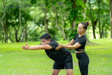 A man and a woman are practicing yoga in a park