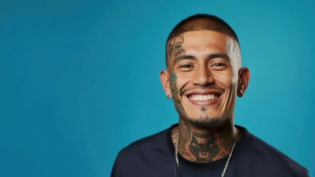 Young Latino man with face and neck tattoos smiling
