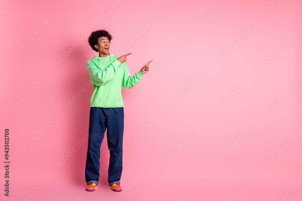 Sticker full body portrait of cool young man indicate fingers empty space wear green hoodie isolated on pink