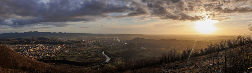 Fototapeta premium ampia composizione panoramica con vista dalla cima di un alto monte, sul vasto territorio tra pianura e collina della regione Friuli Venezia Giulia, nel nord est Italia, al tramonto