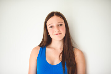 Obraz premium portrait of a 14 years old teen girl close to a white wall with colored shirt
