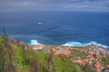 Blick von der Steilküste auf ein Fischerdorf an Madeiras Nordküste