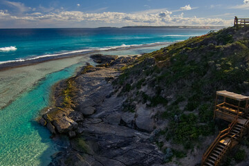 Fototapeta premium A coastal beach with crashing waves wrapped by a sandy hillside
