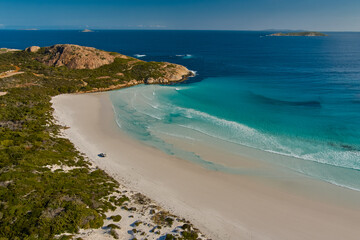 A turquoise ocean with sandy beach and rocky hills