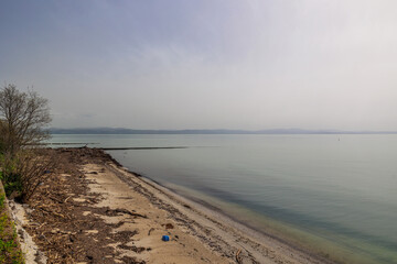 ampia visuale panoramica da una spiaggia sul mare Adriatico guardando verso la costa lontana di Trieste con le sue colline e le montagne, avvolto dalla foschia, di giorno, in estate