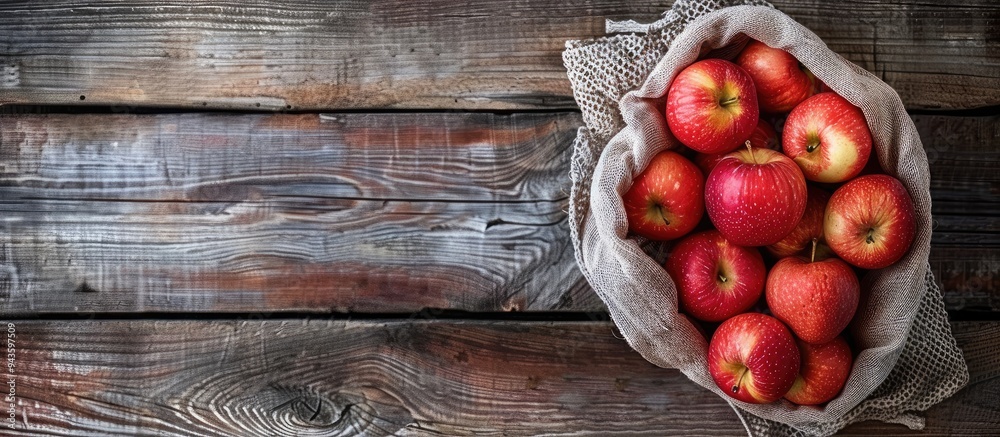 Poster Top view of a wooden background holding freshly arranged red apples in a grid bag perfect for a copy space image