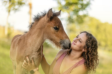 A woman cuddles with a cute icelandic horse foal