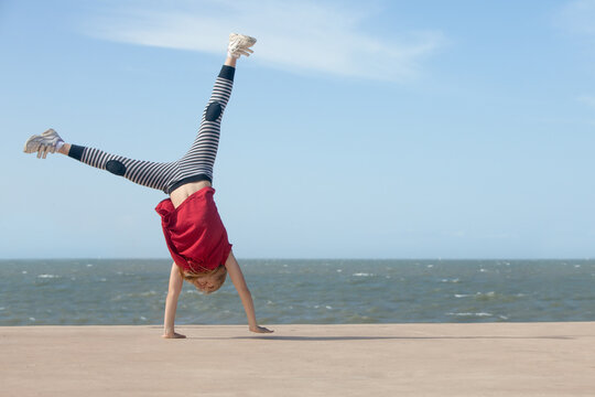 cheerful little girl doing cartwheel by the ocean