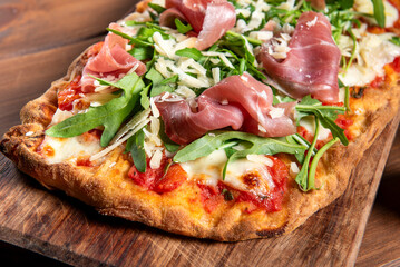 Pinsa condita con prosciutto crudo, parmigiano, rucola, sugo e mozzarella, cibo italiano