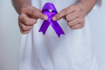 A person holding a purple ribbon, symbolizing awareness and support for various causes, including...