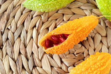 Ripe karela (bitter melon, Momordica charantia) with orange and green color on bamboo table. Top view. Organic fresh tropical fruit.