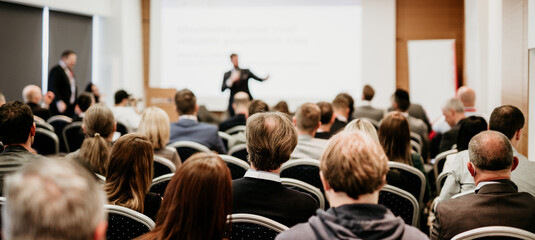 Speaker giving a talk in conference hall at business event. Rear view of unrecognizable people in...