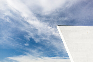 Detail eines Gebäude mit weißer Betonwand. Architektur vor Himmel im Hintergrund.
Detail of a building with white concrete wall. Architecture against the sky in the background.