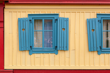 Schiefe blaue Fenster. Lustige Architektur. Herz in Fensterladen. Crooked blue windows. Funny architecture. Heart in shutter.
