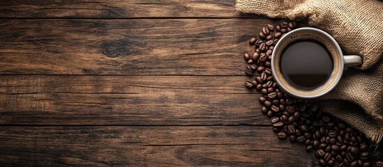 a warm cup of coffee with a sack beside coffee beans on a wooden background. with copy space image. Place for adding text or design